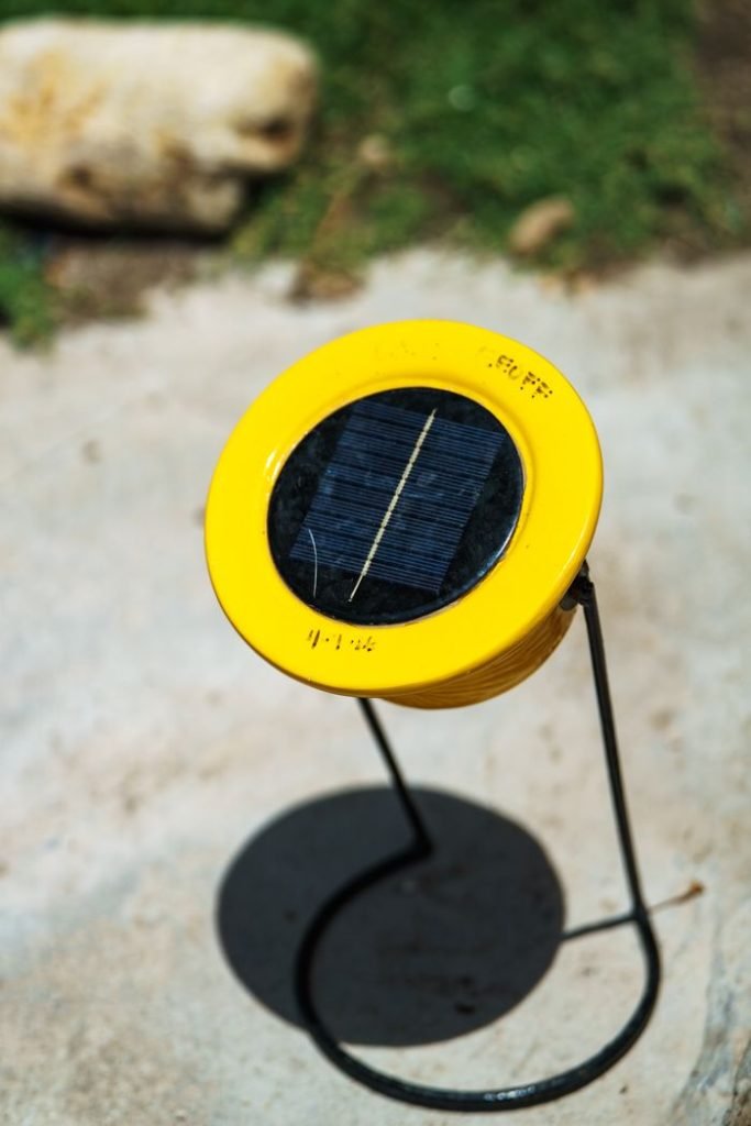 yellow-solar-garden-light-on-stand-outdoors-38603325 A yellow solar-powered garden light stands outdoors on a sunny day, casting a shadow.